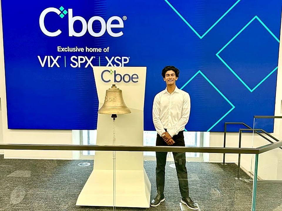 Gabriel Olasa at Cboe headquarters, standing next to the exchange's ceremonial bell